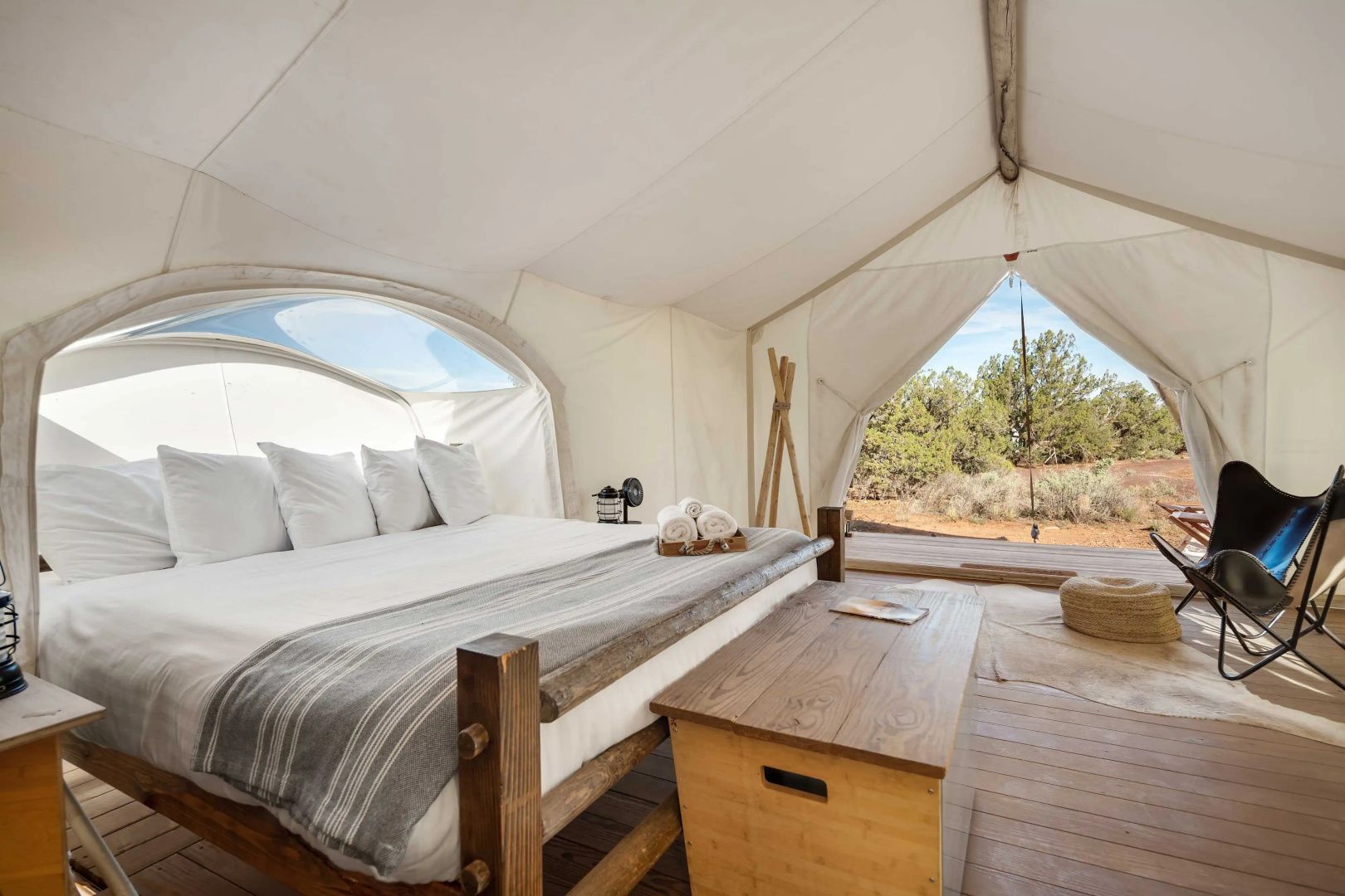 Großes Doppelbett in einem hellen Glampingzelt mit Blick in die Natur.