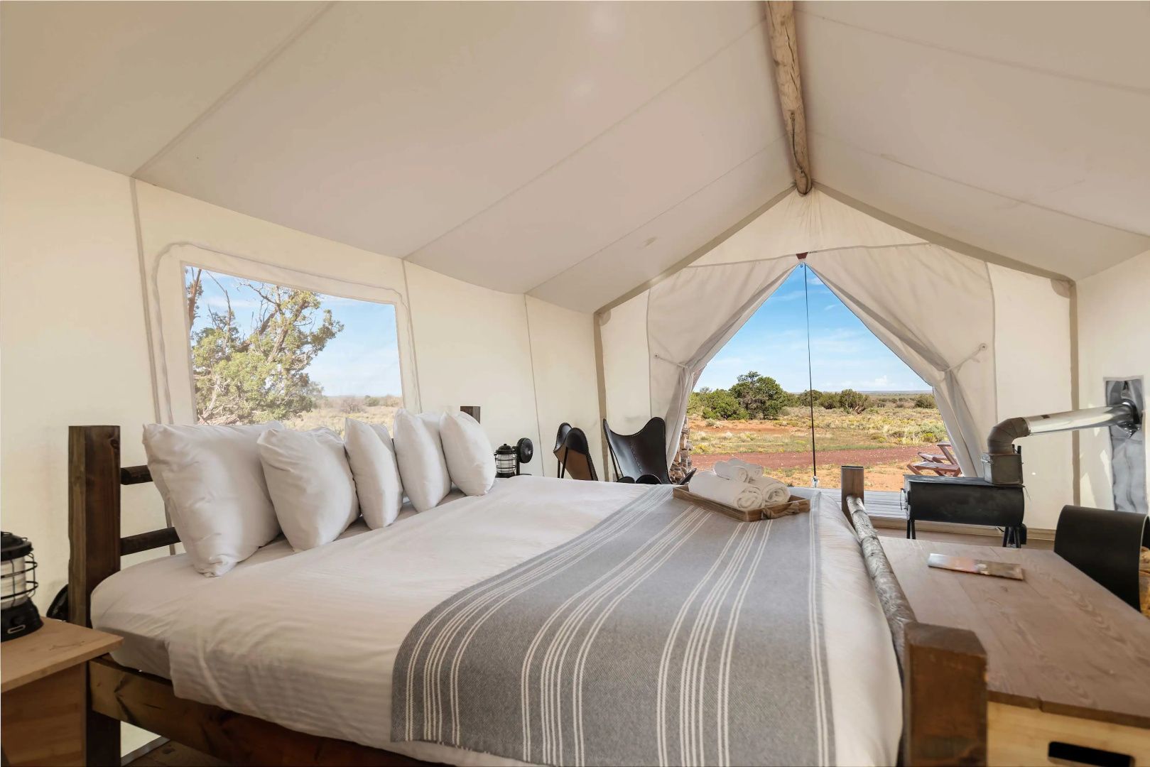 Doppelbett in einem Safari-Zelt mit Blick auf die Landschaft durch große Fenster.