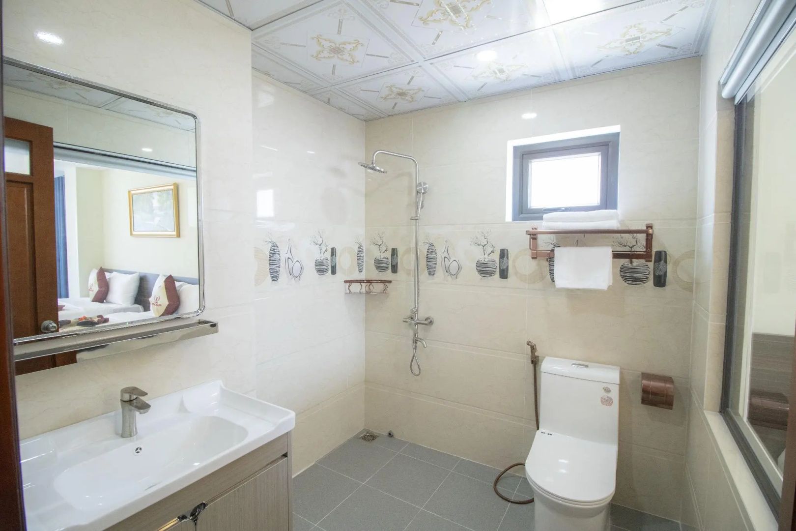 Helles Badezimmer mit Dusche, Toilette, Waschtisch und gefliesten Wänden.