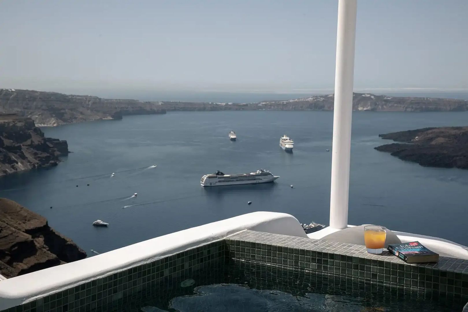 Blick von einem Jacuzzi auf das Meer mit vorbeifahrenden Kreuzfahrtschiffen.