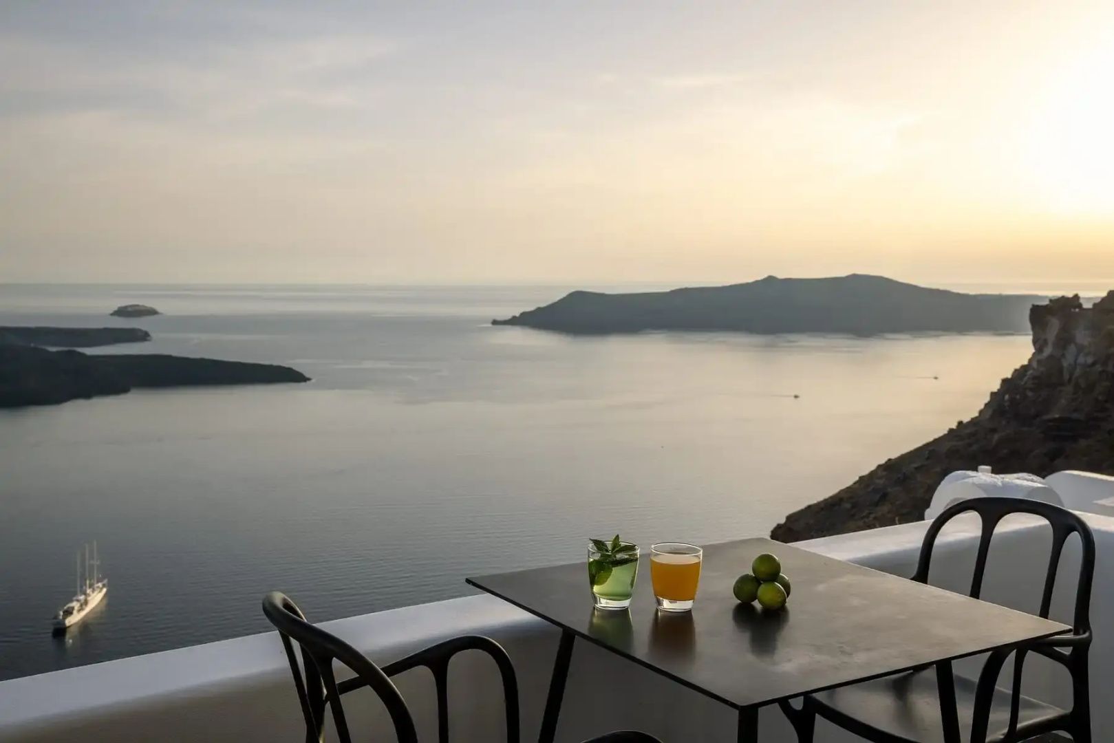 Ein kleiner Tisch auf einer Terrasse mit zwei Gläsern vor der Kulisse des Meeres.