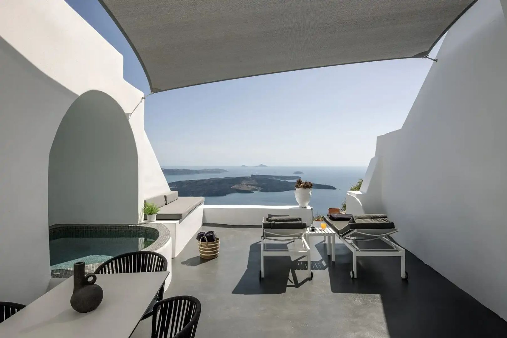 Sonnige Terrasse mit zwei Liegestühlen, Sitzbereich und Weitblick über das Meer.