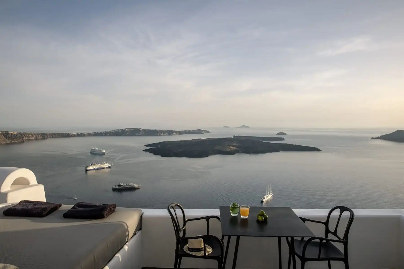 Terrasse mit Tisch und Stühlen und weitem Blick über das Meer und Vulkaninseln.