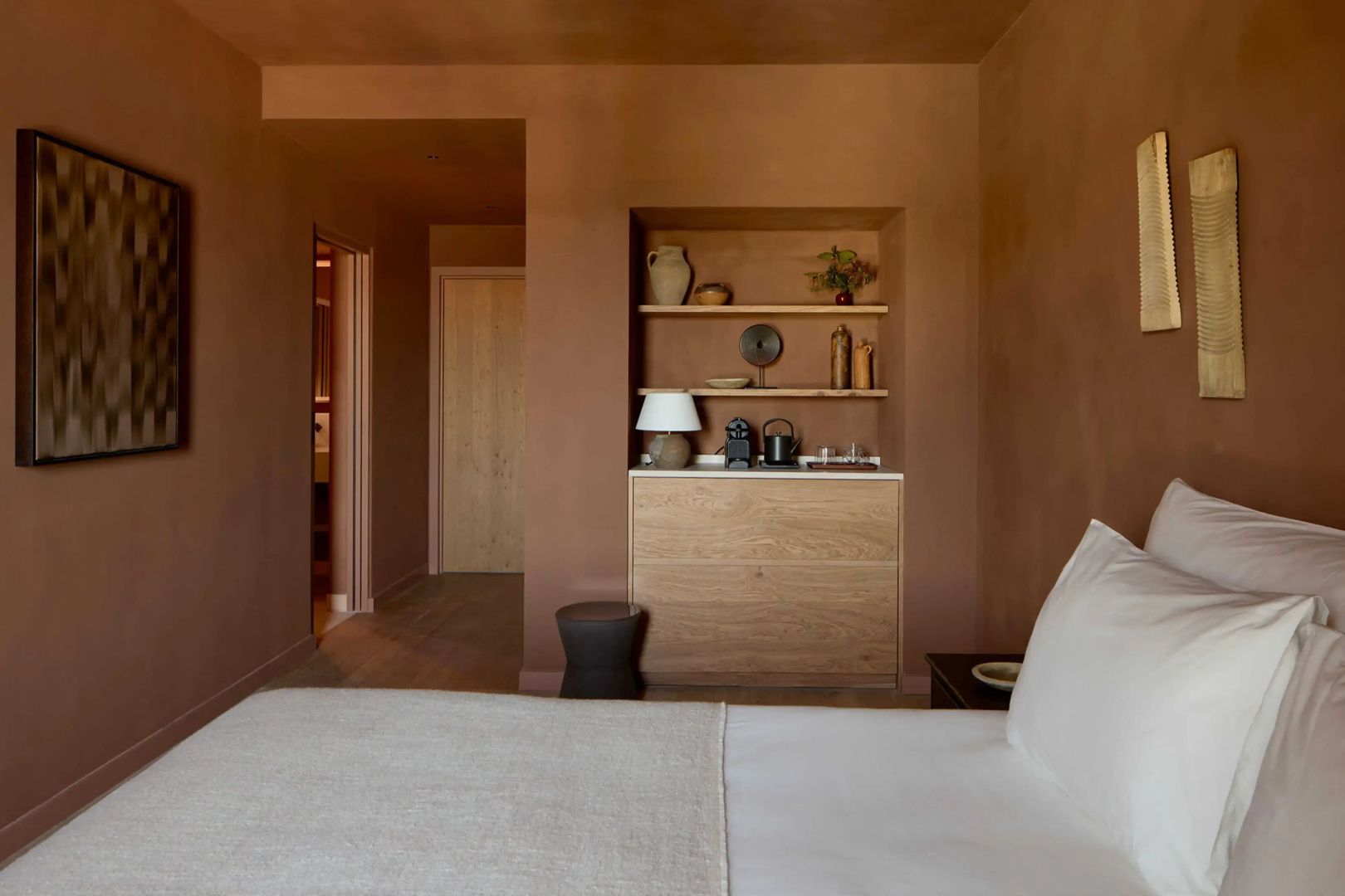 Schlafzimmer mit Einbauregal, Kaffeemaschine auf dem Sideboard und beige braunen Wänden.