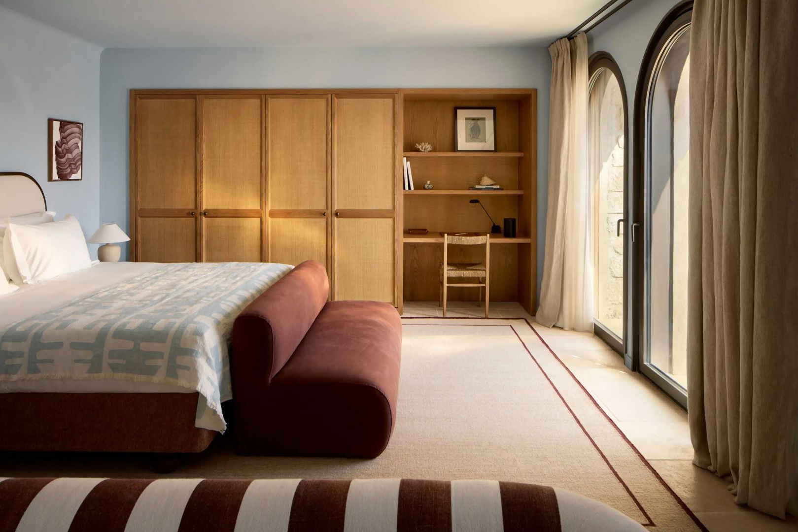 Schlafzimmer mit großem Holzschrank, integriertem Schreibtisch und Polsterbank.