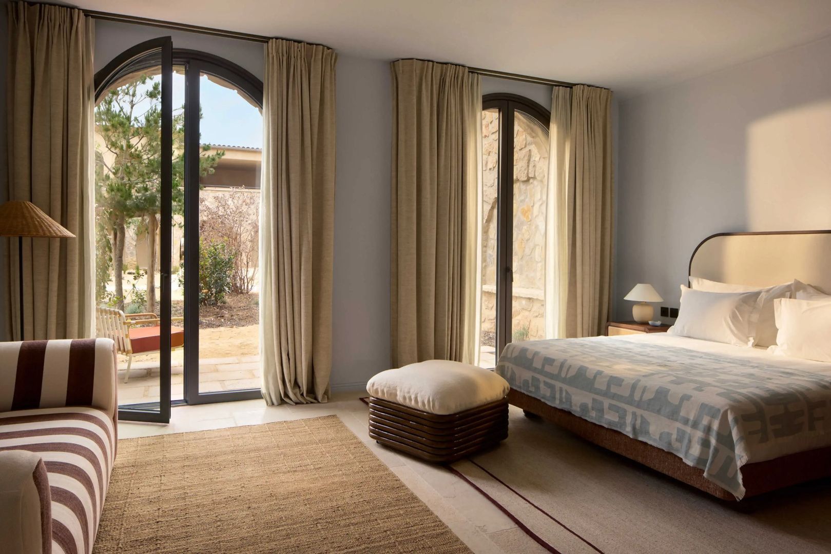 Helles Hotelzimmer mit Doppelbett, Teppich und großen Bogenfenstern zum Innenhof.