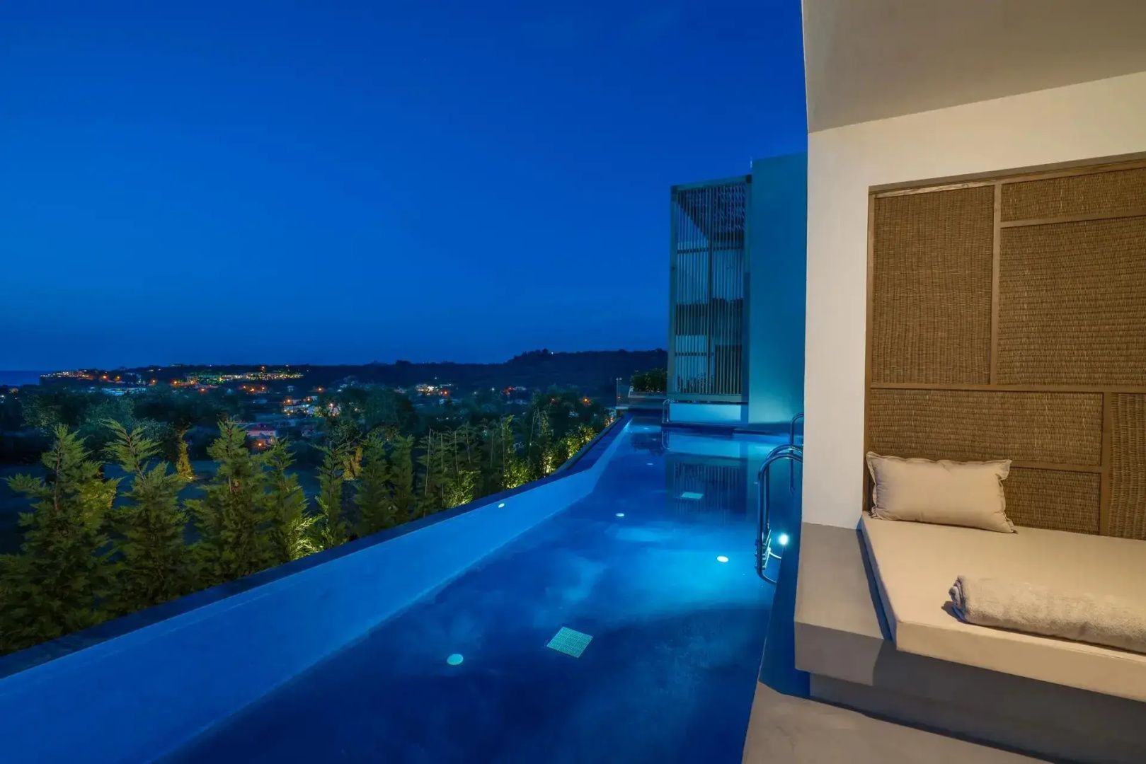 Beleuchteter Infinitypool am Abend mit Blick auf die umliegende Landschaft.