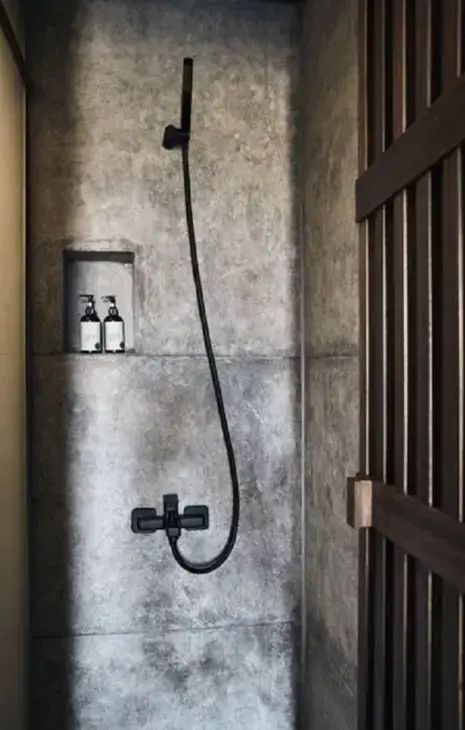 Ebenerdige Dusche mit grauer Steinwand, schwarzer Regendusche und integrierter Ablagenische.