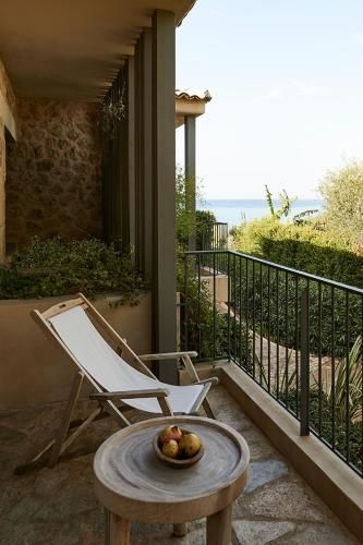 Balkon mit einem Liegestuhl, Holzbeistelltisch und Blick auf das Meer.