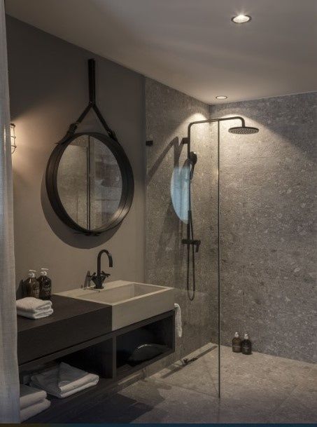 Badezimmer mit rundem Spiegel, Waschtisch und begehbarer Regendusche.