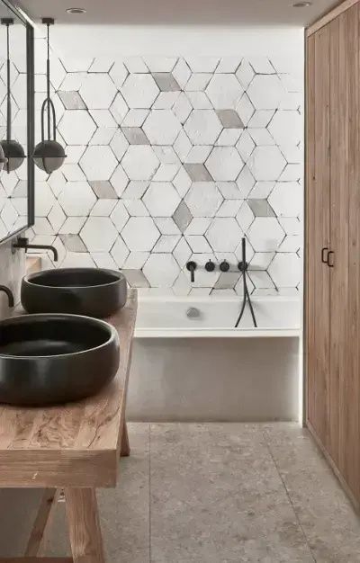 Badezimmer mit zwei dunklen Aufsatzwaschbecken, Holzwaschtisch und einer Badewanne.
