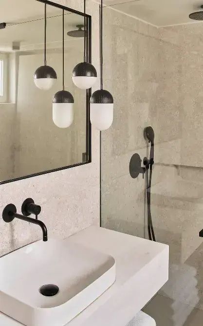 Moderner Waschtisch mit schwarzer Armatur, Hängeleuchten und angrenzender Dusche.