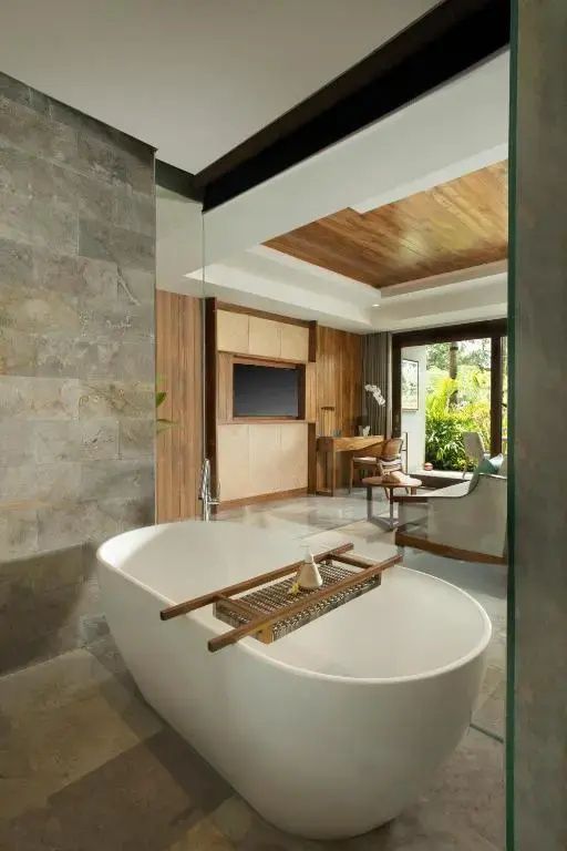Blick aus dem Badezimmer mit weißer Wanne in den angrenzenden Wohn- und Schlafbereich.