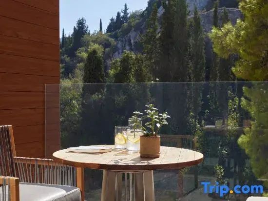 Holztisch auf einem Balkon mit Blick auf Zypressen und bewaldete Hügel
