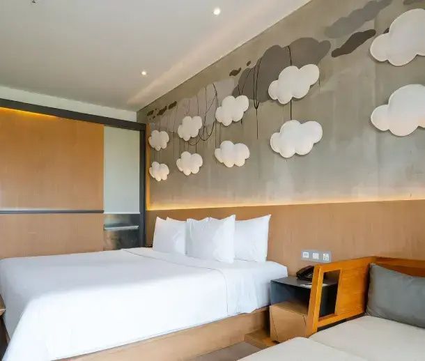 Modernes Hotelzimmer mit Doppelbett, weißer Bettwäsche und Wolkendesign an der Wand.