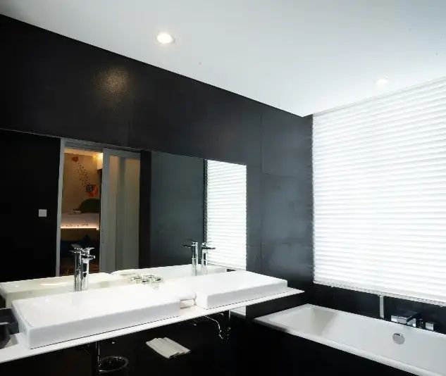 Modernes Badezimmer mit schwarzer Wand, großem Spiegel, weißem Doppelwaschbecken und Badewanne.