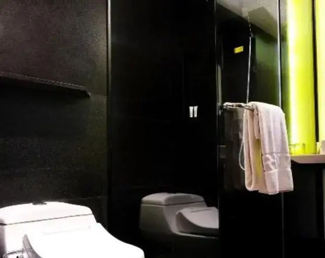 Dunkel gestaltetes Badezimmer mit Toilette und Dusche mit Glastür.