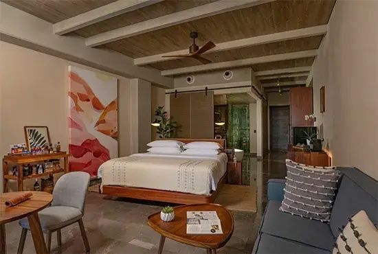 Geräumiges Hotelzimmer mit Doppelbett, Sitzbereich, Deckenventilator und Holzdecke