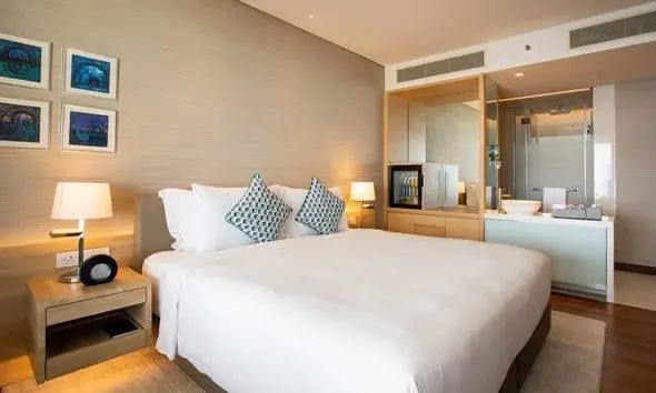 Doppelbett mit weißer Bettwäsche und Kissen in einem hell gestalteten Hotelzimmer.