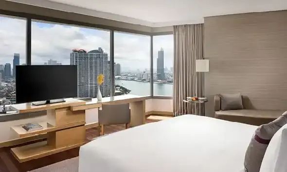 Blick aus einem Hotelzimmer durch große Eckfenster auf den Fluss und Hochhäuser.