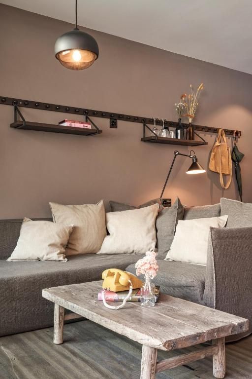 Sitzecke mit grauem Ecksofa, Kissen, Holztisch und gelbem Telefon.