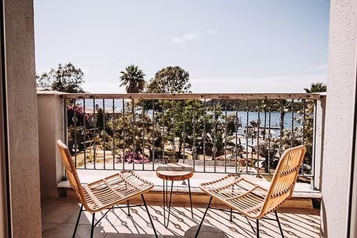 Balkon mit zwei Stühlen und Beistelltisch sowie Blick auf den Garten und das Meer.