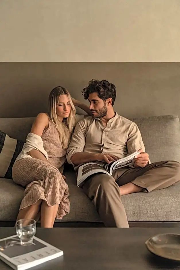 Ein Paar sitzt entspannt auf dem Sofa in einem modern gestalteten Hotelzimmer.