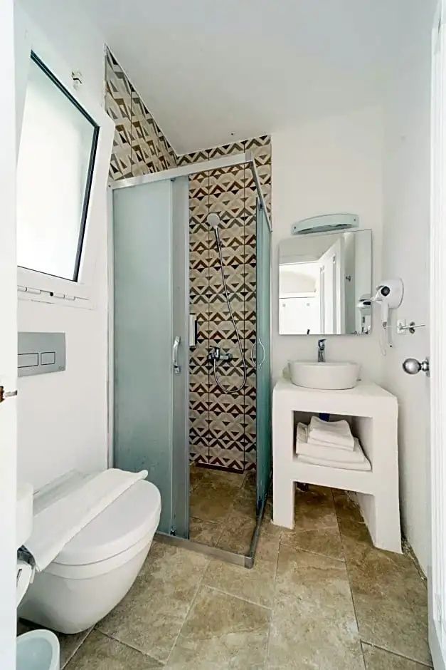 Badezimmer mit einer Dusche, weißer Toilette und einem Waschtisch mit Spiegel.