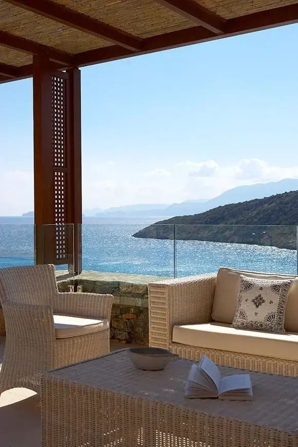 Terrasse mit Rattanmöbeln und freiem Blick auf das Meer und die Bucht.