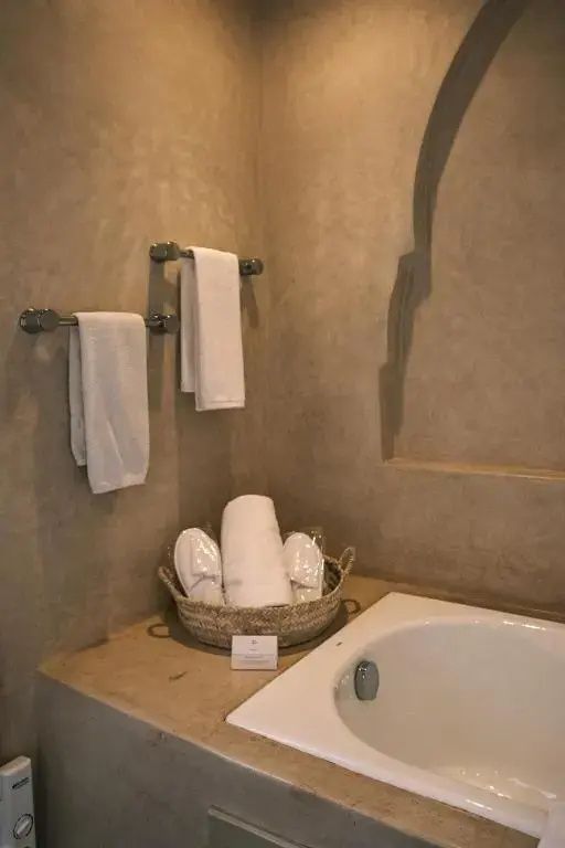 Badezimmer mit einer Badewanne, Handtüchern an der Wand und Pflegeutensilien.
