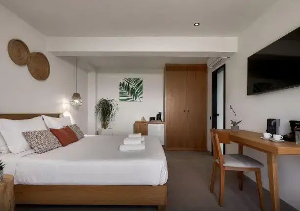 Modernes Doppelzimmer mit Holzschrank, Schreibtisch und Fernseher an der Wand.