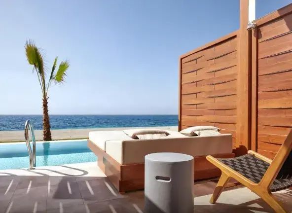 Terrasse mit Liegebett und Beistelltisch mit direktem Blick auf den Pool und das Meer.