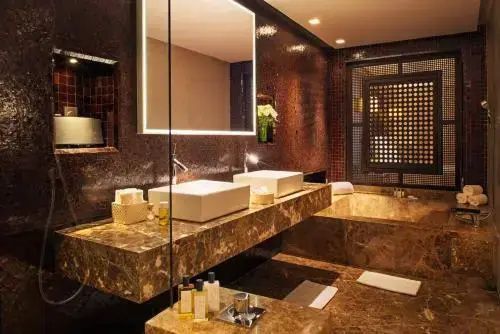 Badezimmer mit doppeltem Waschtisch, beleuchtetem Spiegel und Badewanne.