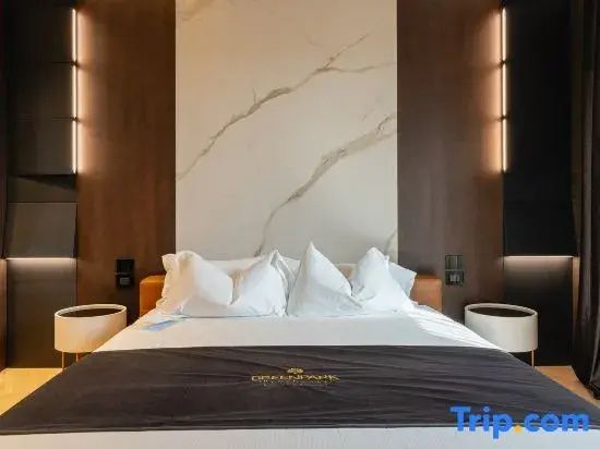 Doppelbett mit weißen Kissen und Marmorwand im Schlafbereich der Suite.