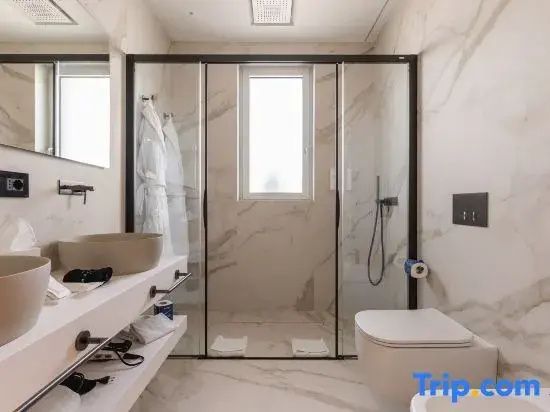 Badezimmer mit ebenerdiger Glasdusche, Wand-WC und hellem Waschtisch mit Marmoroptik.