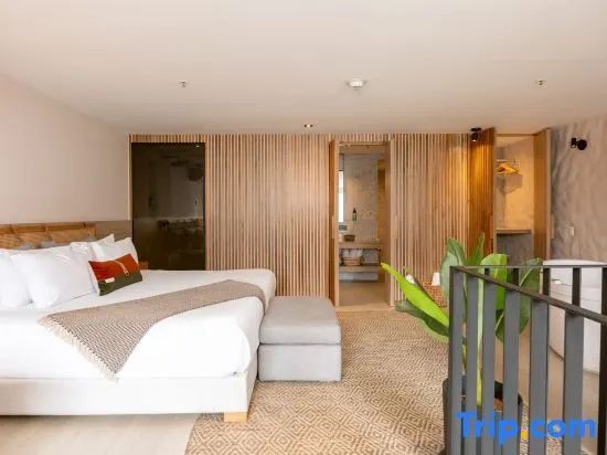Helles Hotelzimmer mit Doppelbett, Holzverkleidung an der Wand und Blick ins Bad.