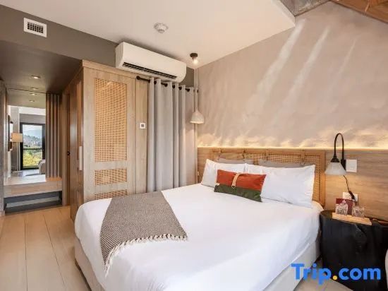 Hell gestaltetes Hotelzimmer mit Doppelbett, Klimaanlage und Holzverkleidung.