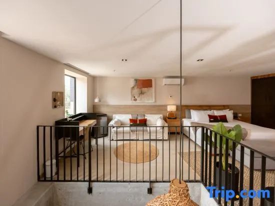 Geräumige Suite mit Sofa, Schreibtisch, Doppelbett und Geländer zur Treppe.