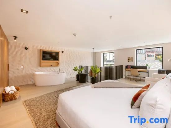 Offene Suite mit freistehender Badewanne, großem Bett und Schreibtisch am Fenster.