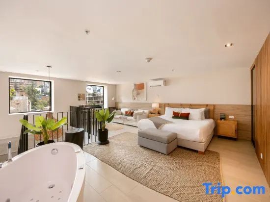 Großzügiges Hotelzimmer mit freistehender Badewanne, Doppelbett und Sofaecke.