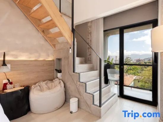 Maisonette Zimmer mit Beton Treppe nach oben und Zugang zum Balkon durch Glas Schiebetür.
