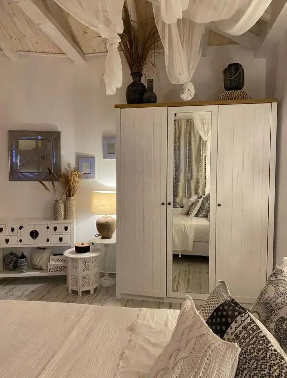 Weißer Kleiderschrank mit Spiegeltür in einem hell eingerichteten Schlafzimmer.