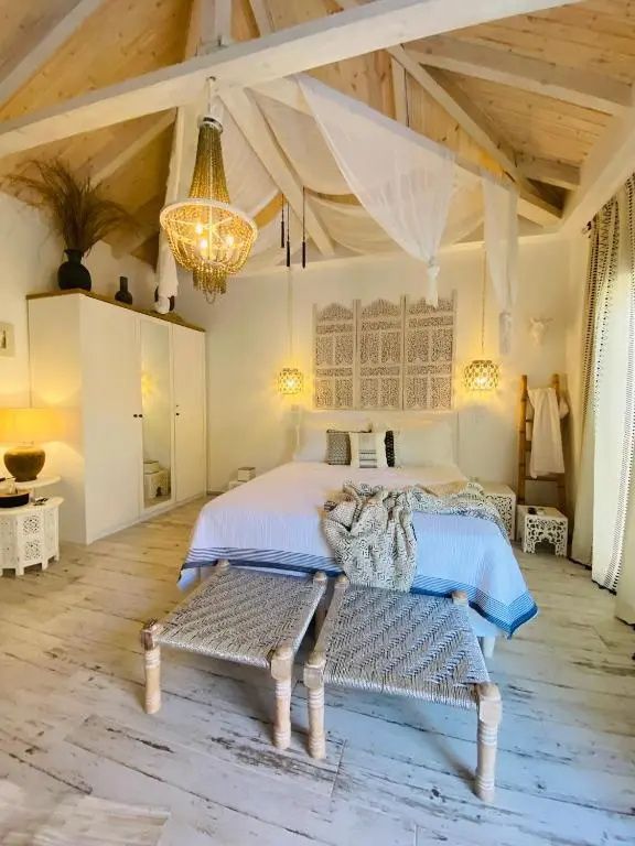 Schlafzimmer im Boho-Stil mit einem großen Doppelbett, Holzdecke und Dekoration.