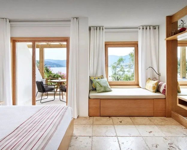 Sitzfenster mit Kissen in einem Zimmer mit Ausblick auf das Meer und die Hügellandschaft.