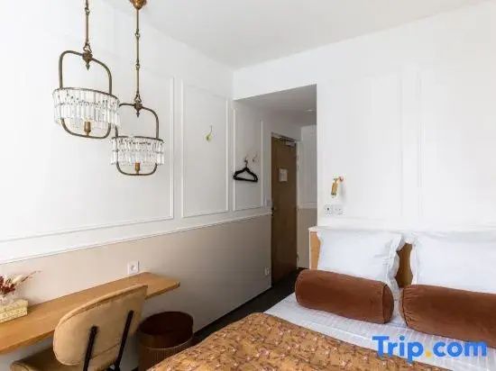 Helles Hotelzimmer mit Doppelbett, hängenden Kristallleuchten und kleinem Schreibtisch an der Wand.