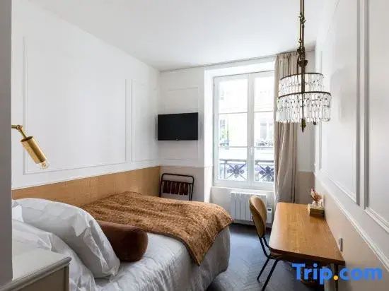 Schlafbereich mit gemachtem Bett, Holzschreibtisch und hohem Fenster in der Außenwand.