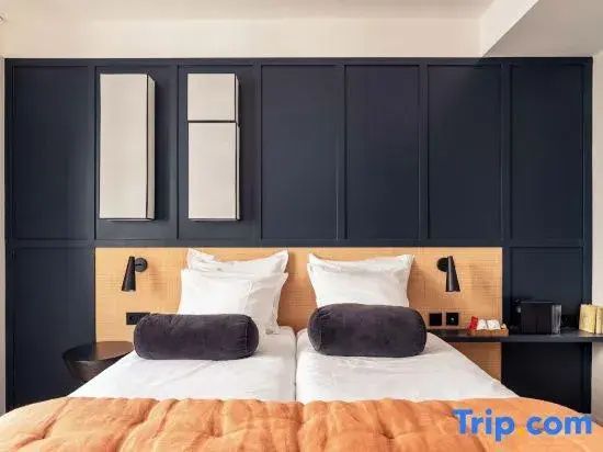 Doppelbett mit weißen Kissen vor einer dunkelblauen Wand mit hölzernen Elementen.