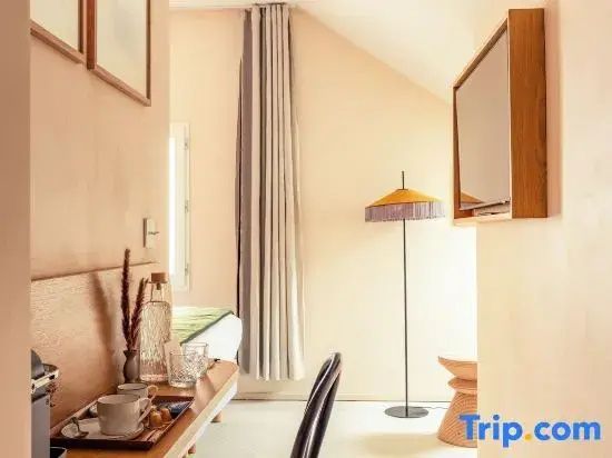 Helles Hotelzimmer mit gelber Stehlampe und Tisch mit Kaffeetassen.
