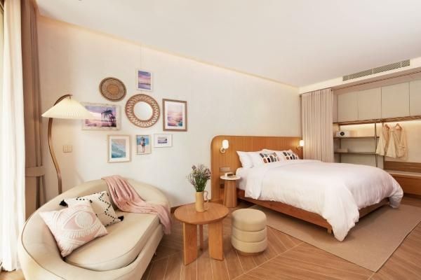 Heller Schlafraum mit großem Doppelbett, kleinem Sofa und Wanddekorationen.