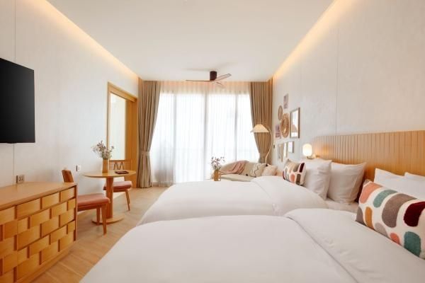 Geräumiges Hotelzimmer mit zwei Betten, Sitzgruppe und großer Fensterfront.